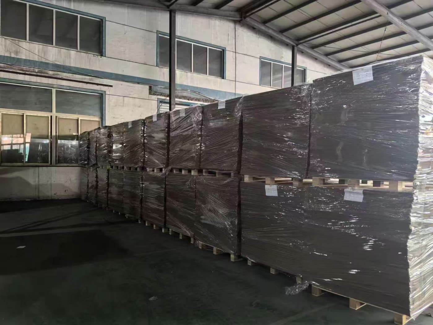 批量连续纸板托盘在仓库内完成缠绕包装并等待出库